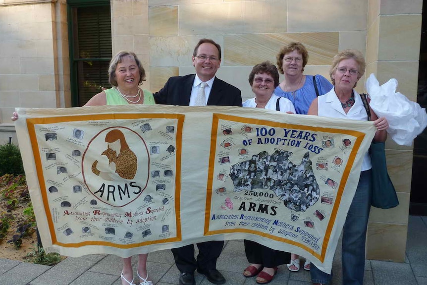 Women standing with Government minister and holding up a banner