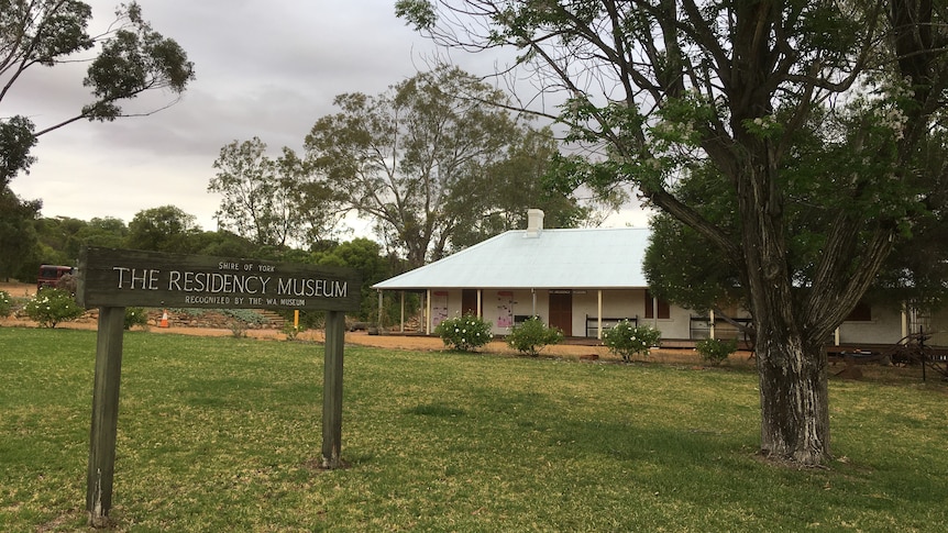 Photo of whitewashed heritage building with veranda under trees with a sign out the front saying 'Residency Museum'.