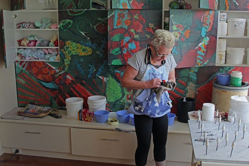 A lady holding a baby bat in her living room.