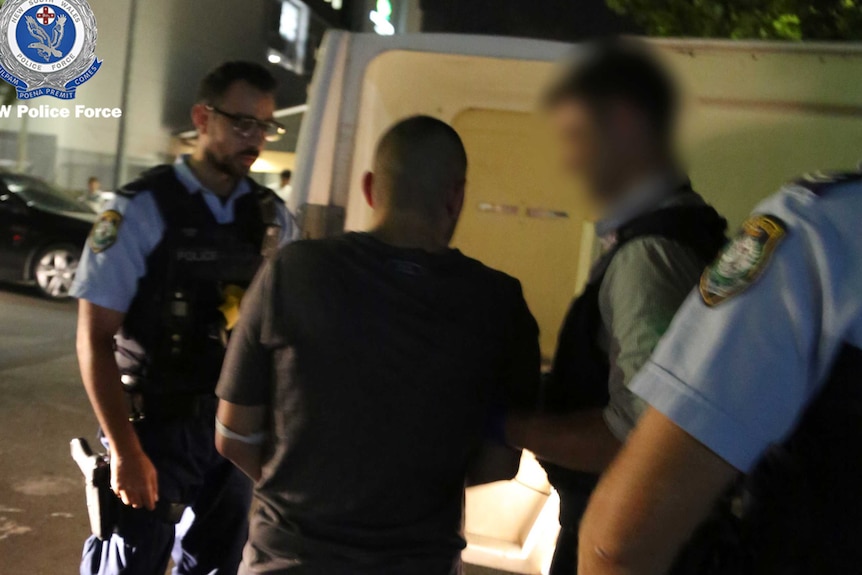 A man is is led to a police van by officers.