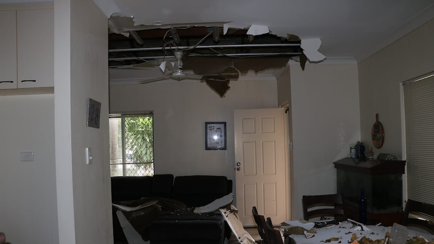 A room scattered with pieces of a ceiling that has caved 