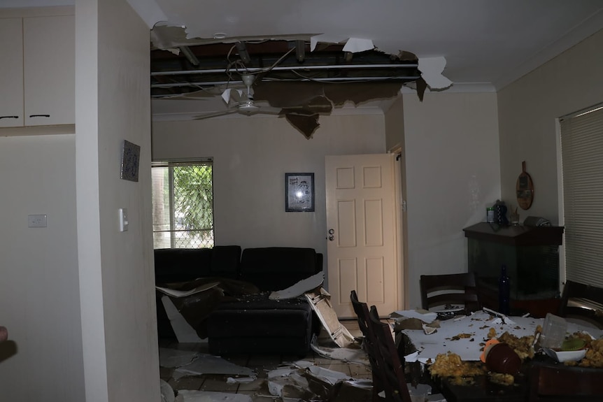 A room scattered with pieces of a ceiling that has caved 