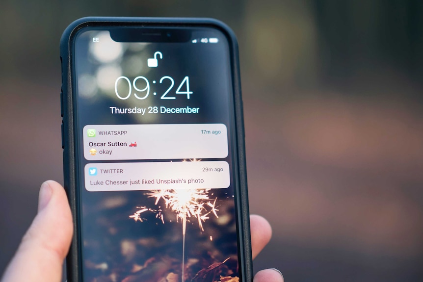 Person holding a smartphone in their hand and checking their social media notifications.