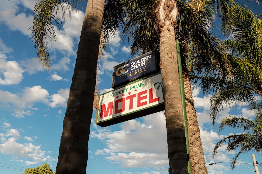 A sign for the Foundry Palms Motel sits amid palm trees