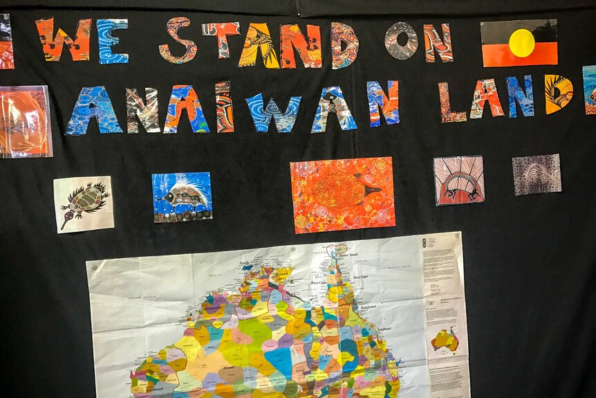 An artwork wall that says "We Stand On Anaiwan Land"