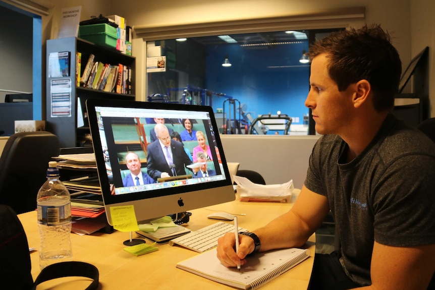 Corey Green watches on his computer a live stream of Treasurer Scott Morrison delivering his 2017 federal budget.