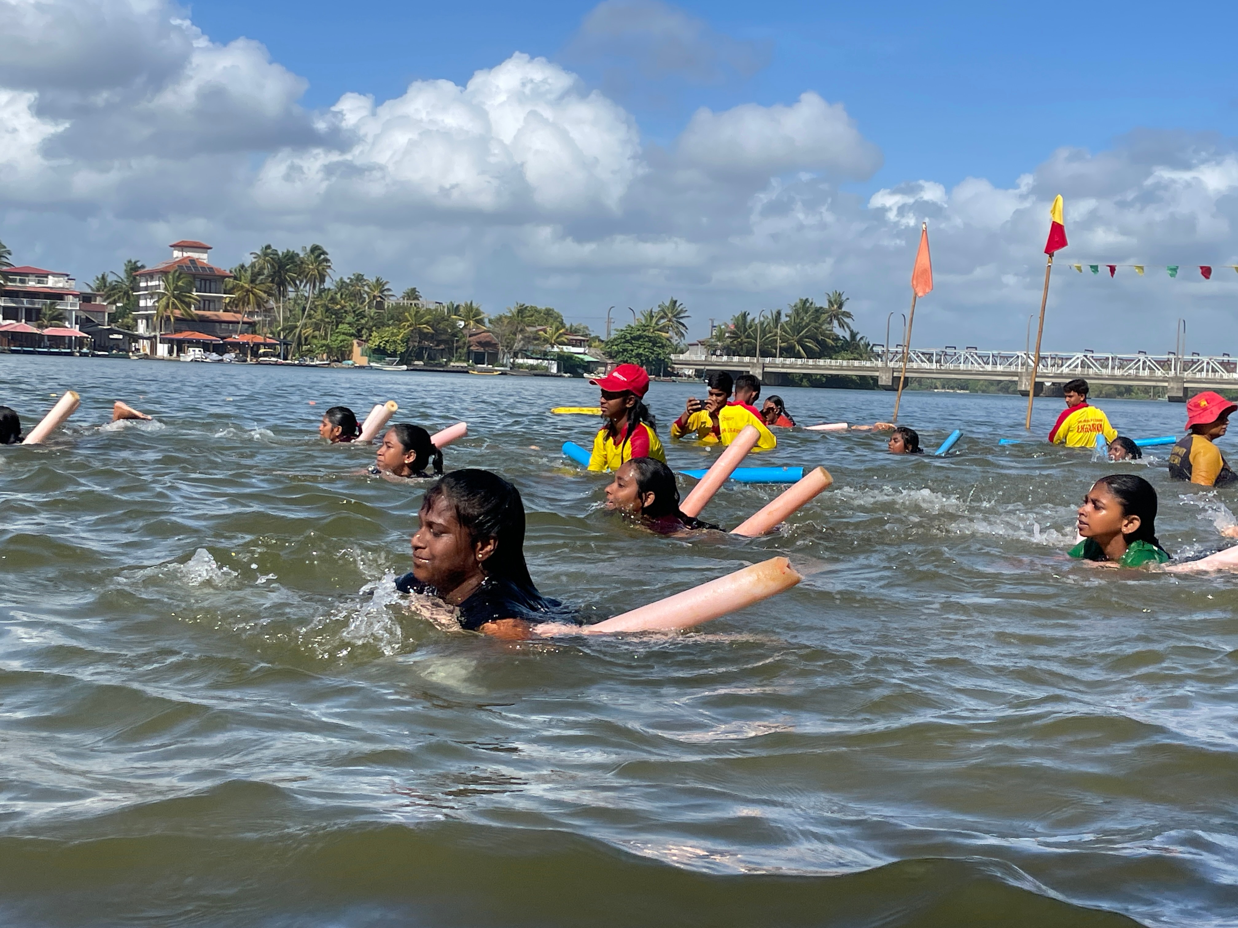 crianças aprendendo a nadar segurando macarrão de espuma 