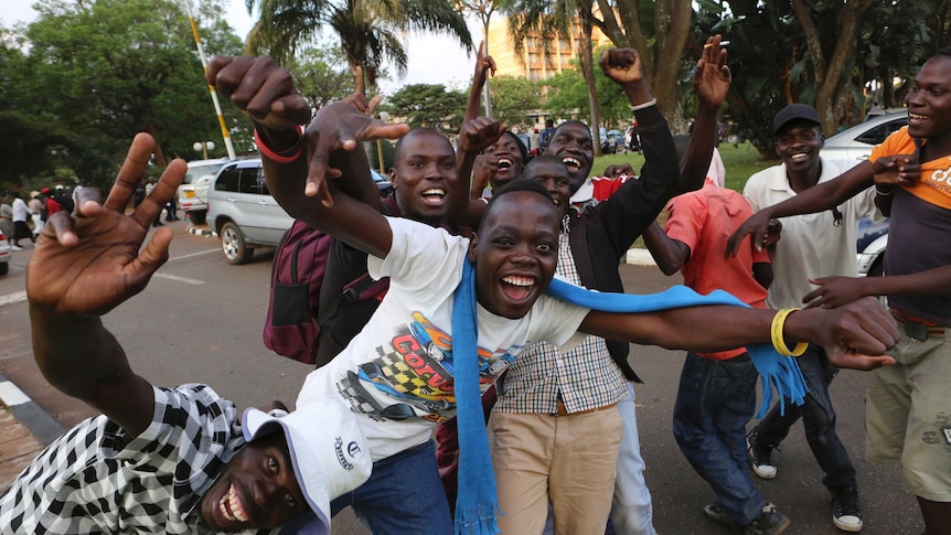 Zimbabweans wave their hands and celebrate on the streets of Harare.