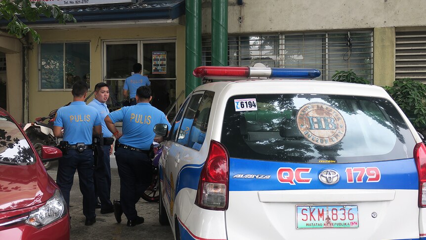 Philippines police stand next to a police car in Quezon City.