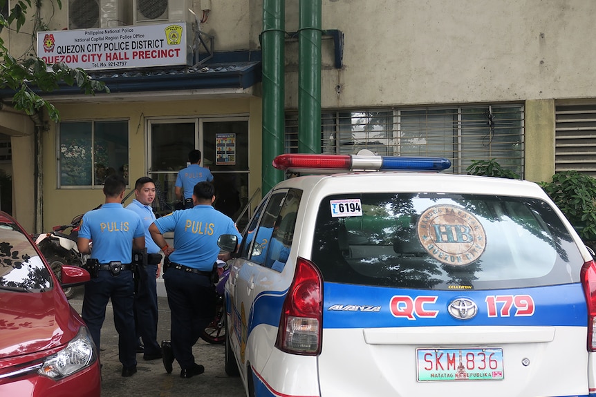 Philippines police stand next to a police car in Quezon City.