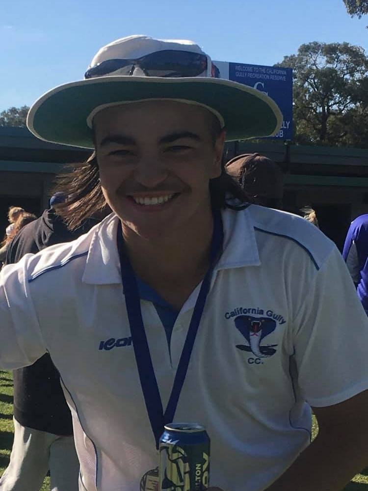 teenager in a cricket hat and white top