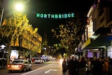 A sign of Northbridge hangs over a street with bright lights and crowds of people