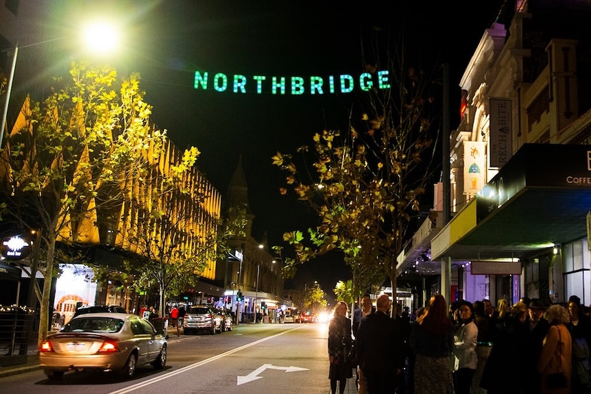 A sign of Northbridge hangs over a street with bright lights and crowds of people