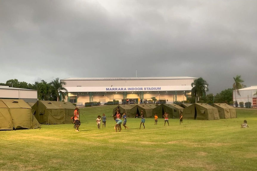 Children play on a lawn in front of tent accommodation.