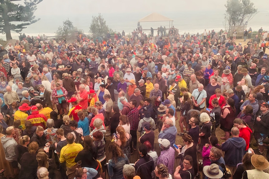 Large crowd gathered with beach in background