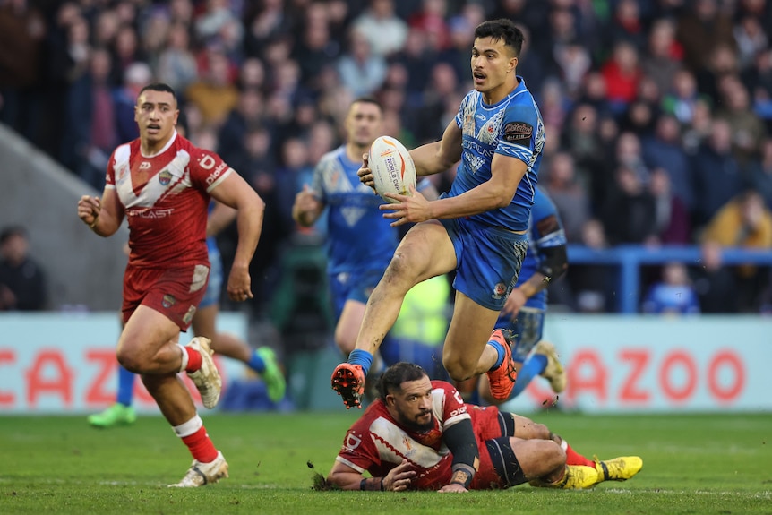 Joseph Suaali’i of Samoa jumps as he runs away from the defence of Tonga at the Rugby League World Cup.