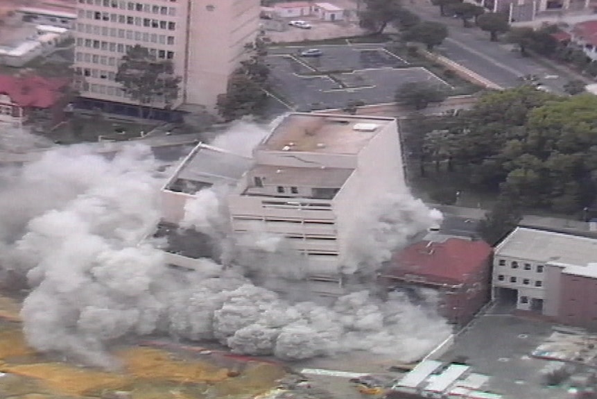 Two buildings being demolished with explosives