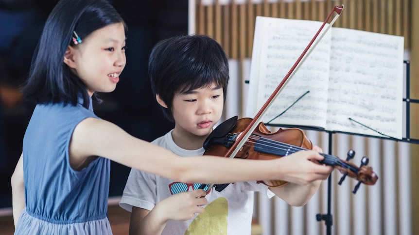 Boy and girl playing violin at home