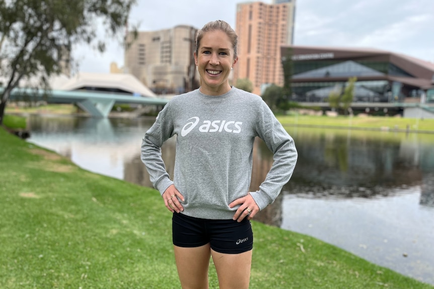 Jess Stenson stands in front of the river torrens with her arms on her hips