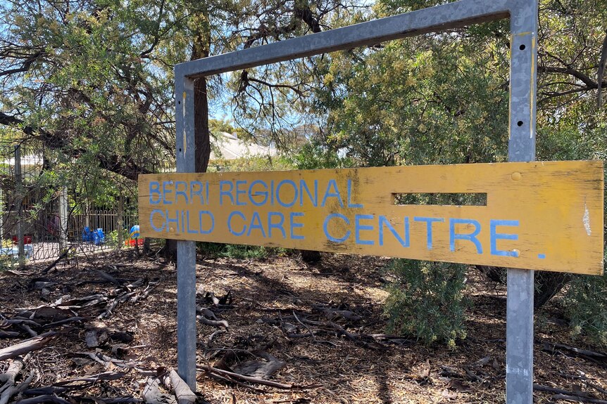A yellow sign with the words Berri Regional Childcare Centre, In the background is a playground