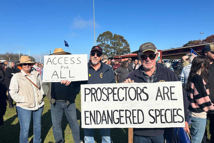 Two men holding signs that read access for all and prospectors are endangered species.