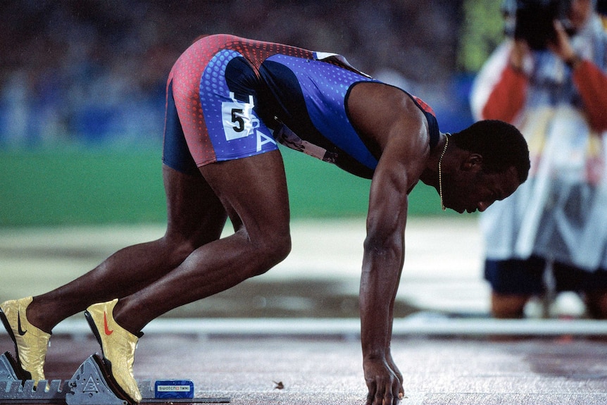 Michael Johnson holds in starting position on the blocks with his arms extended