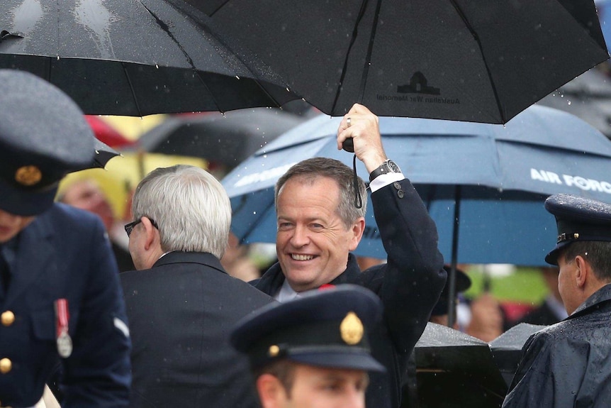 Bill Shorten holds an umbrella in the rain at Remembrance Day service in Canberra.