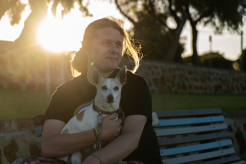 Non-binary person sitting on park bench with dog