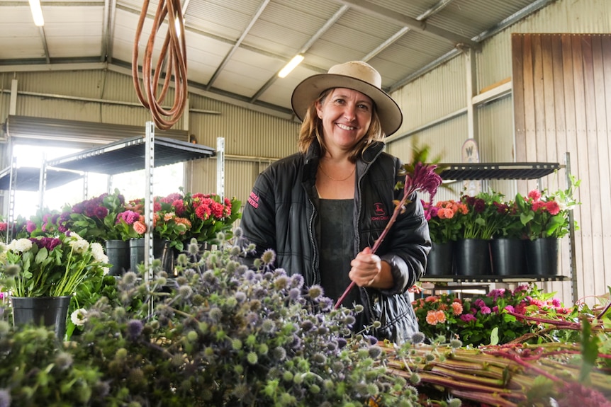 A woman works in a shed with her recently picked flower crop