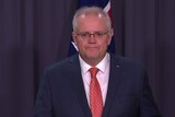 Scott Morrison blows air into his cheeks while standing at a lectern