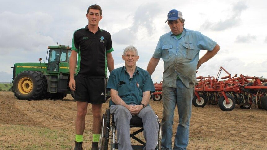 Dandaragan farmer, Ian Minty, sits in a wheelchair between John and grandson Gavin with tractors in the backgorund.