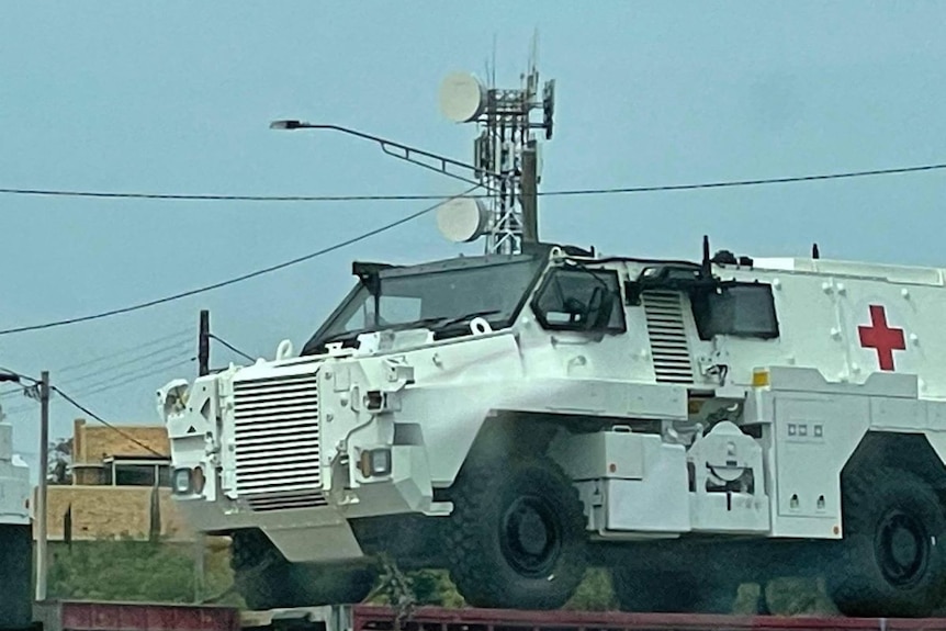 large white jeep like vehicle with a red cross painted on it