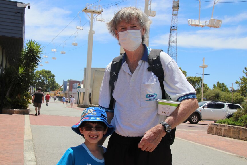 Brian Usher and 7-year-old son John stand outside a vaccination clinic in Perth.