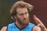 A bearded James Stewart completes his follow through after kicking an AFL ball at Essendon Bombers training.