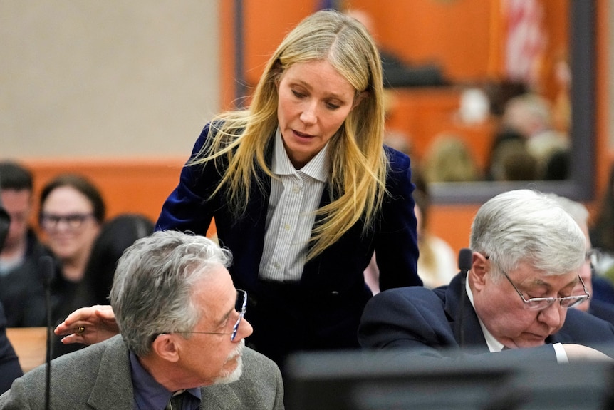Gwyneth Paltrow speaks to an older man sitting in a court room