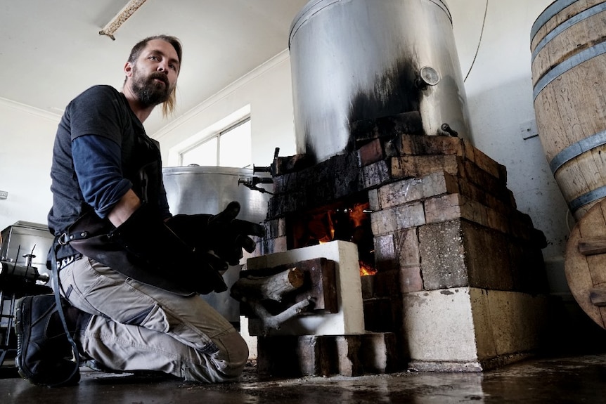 Robe Town Brewery owner Maris Biezaitis stokes a large fire in his brewery.