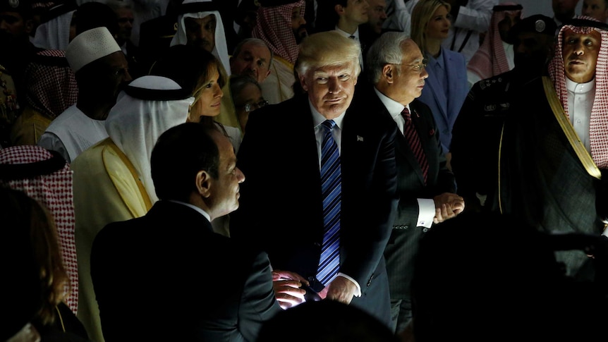 US President Donald Trump stands near Melania and other leaders smirking as he touches a glowing globe of Earth