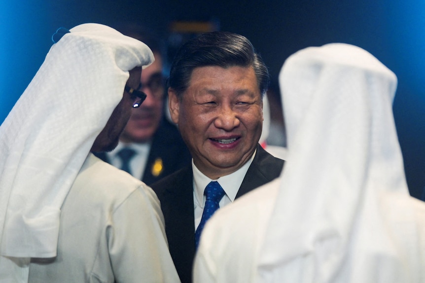 Xi Jinping stands between two men in Saudi headdress 