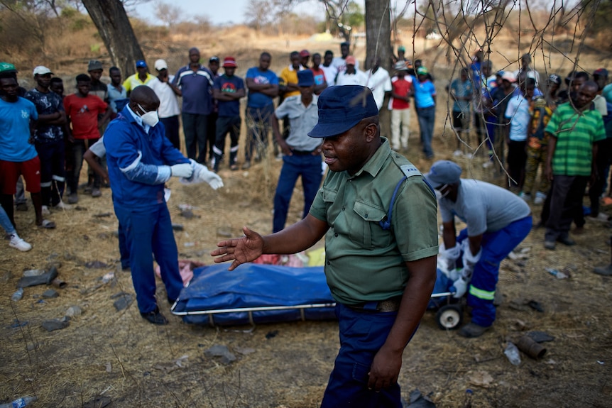 a group of people durround a body in a bag 