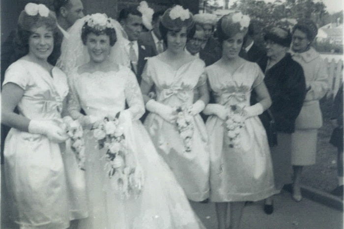 A 1950s bride with three bridesmaids in below the knee dresses.