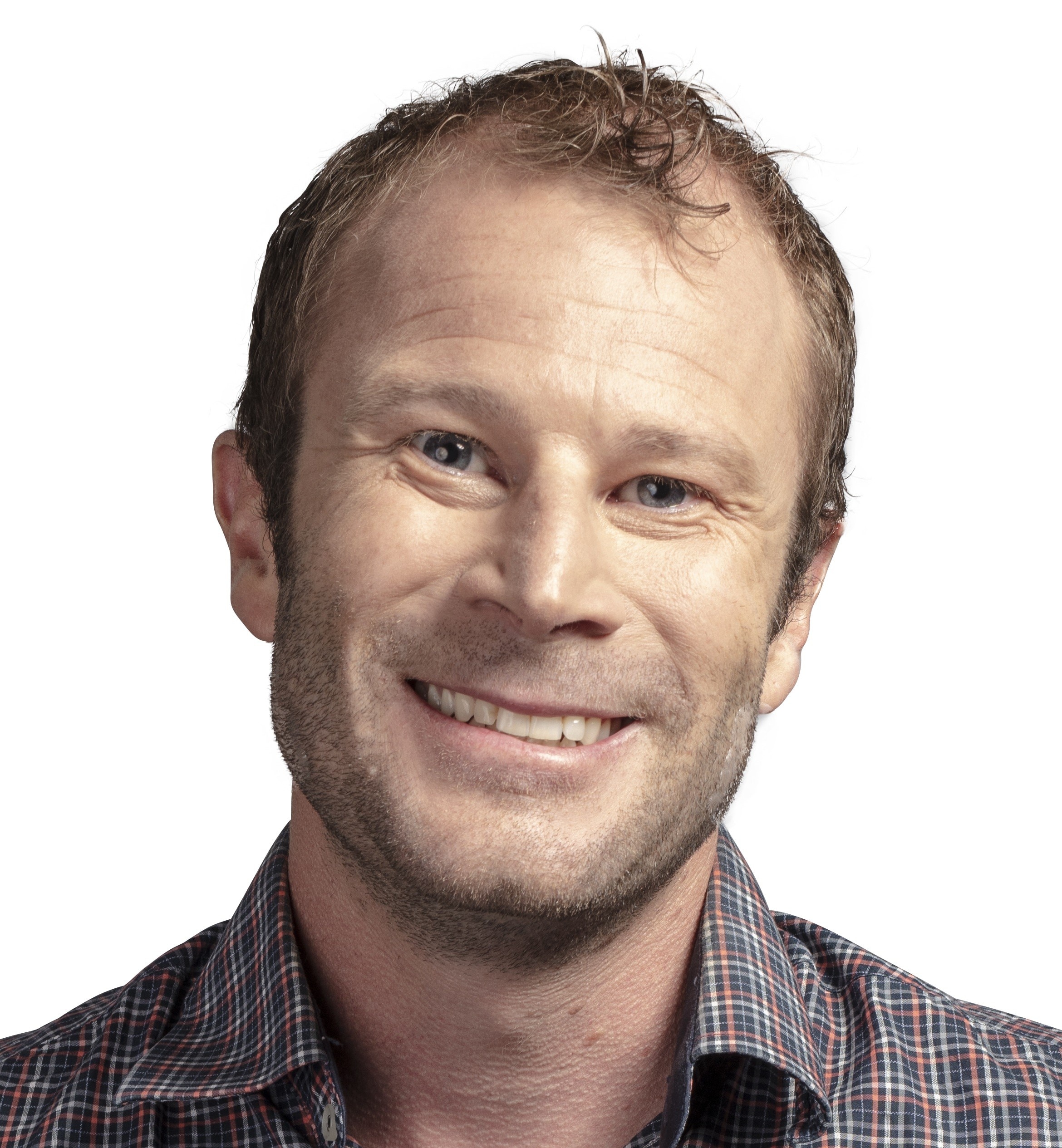 Un hombre sonríe a la cámara con la cabeza inclinada y viste una camisa a rayas.