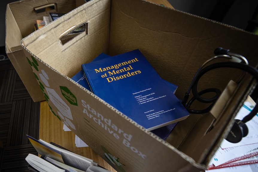 A box sits on a chair, with a book inside it called Management of Mental Disorders 