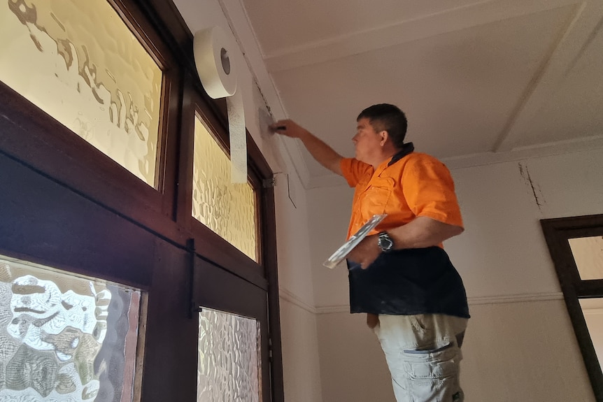 A man wearing hi-vis plastering a wall. 