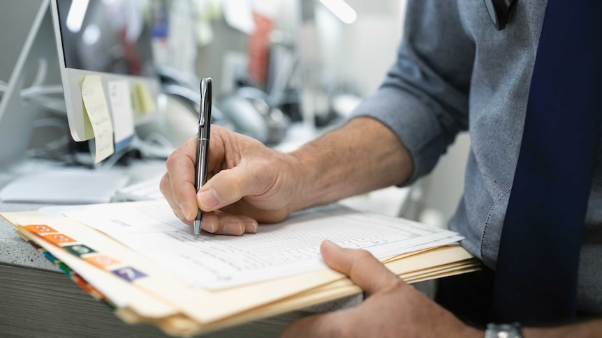 Close up male doctor writing in medical record.