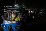 A woman sits in the driver seat of an auto-rickshaw