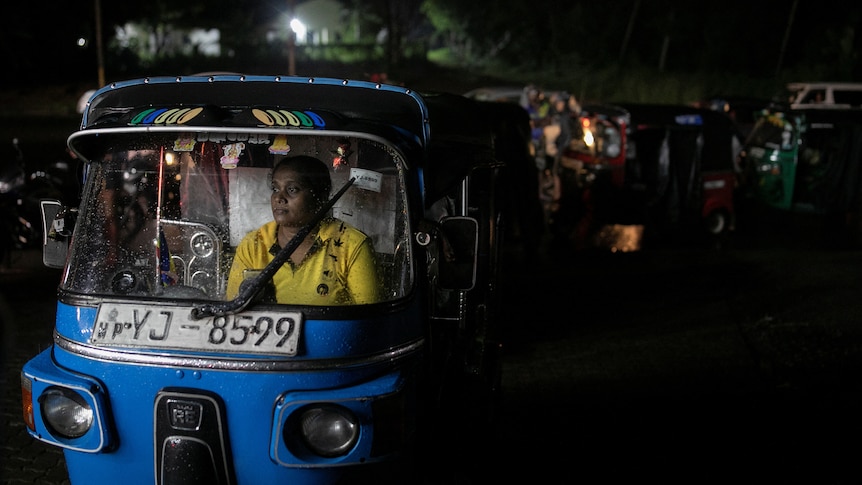 A woman sits in the driver seat of an auto-rickshaw