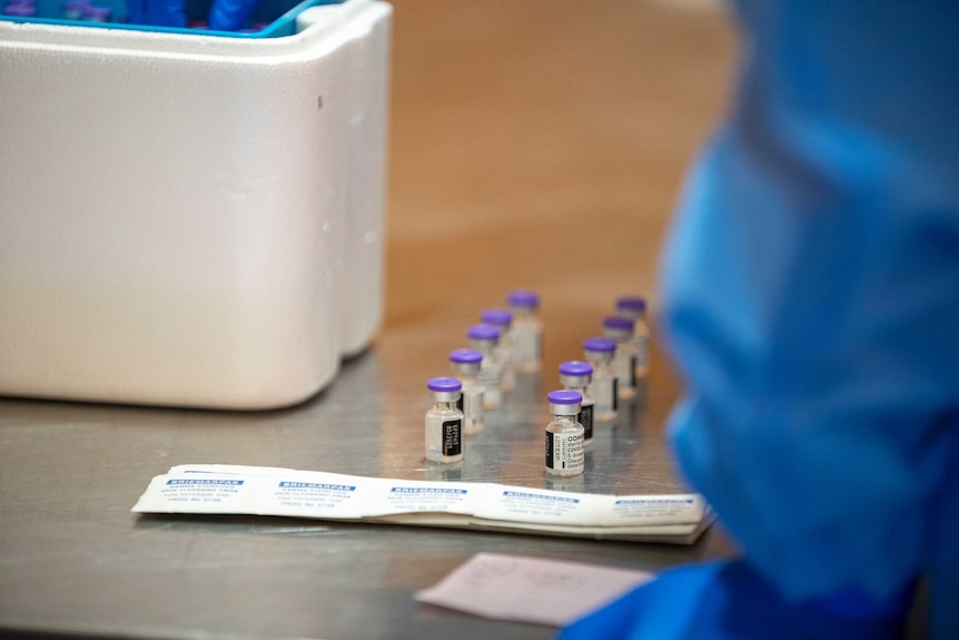 Vials of the coronavirus vaccine in front of a cold storage box on a table.