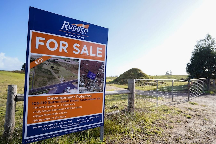 A large For Sale sign stands out the front of a large paddocked area.