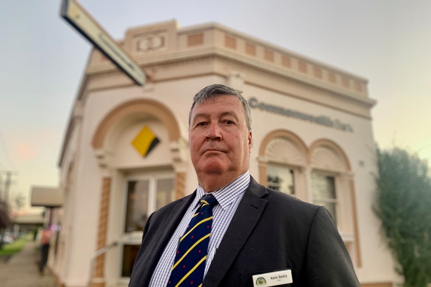A man in a suit stands in front of a Commonwealth Bank branch.