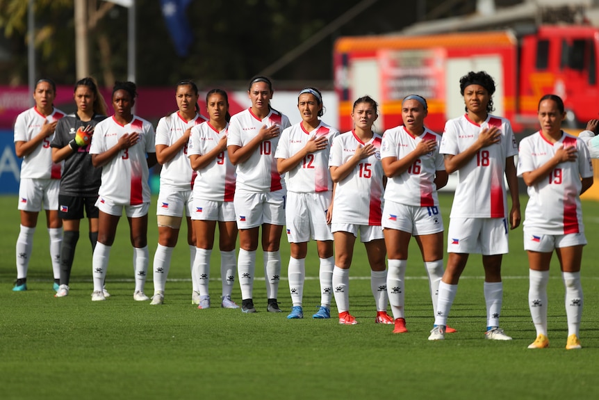 Members of the Philippines women's national football team stand with hands on hearts for national anthem